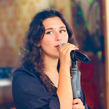Sängerin mit lockigen Haaren singt ins Mikrofon, secret stage, Kieler Woche 2025