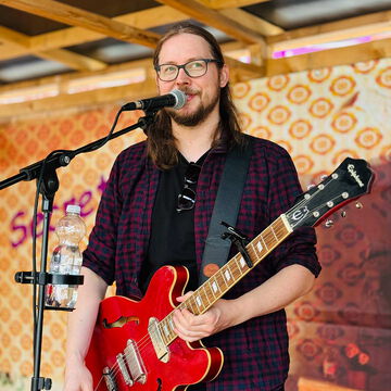 Sänger mit Brille und roter E-Gitarre am Mikrofon, secret stage, Kieler Woche 2025