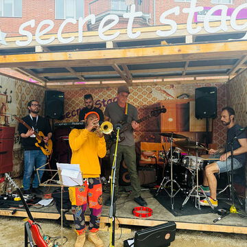 Band mit Trompete, Gitarren und Schlagzeug unter dem secret stage Schriftzug, Kieler Woche 2025