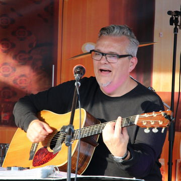 Sänger mit Brille spielt Akustikgitarre auf der secret stage, Kieler Woche 2023