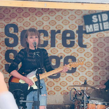 Sängerin mit E-Gitarre vor dem secret stage Schriftzug, Kieler Woche 2025