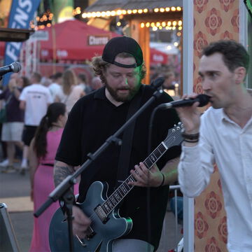 Sänger und Gitarrist auf der secret stage, im Hintergrund Besucher der Kiellinie, Kieler Woche 2026
