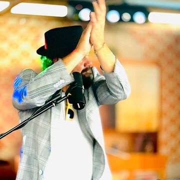 Musiker mit schwarzem Hut klatscht über dem Kopf in die Hände, secret stage, Kieler Woche 2025