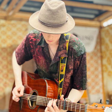 Gitarrist mit Hut und gemustertem Hemd an der Akustikgitarre, secret stage, Kieler Woche 2025