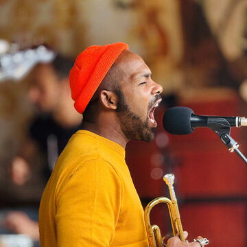 Sänger mit oranger Mütze und Trompete singt ins Mikrofon, secret stage, Kieler Woche 2025