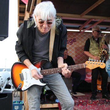 Gitarrist mit weißen Haaren und Sonnenbrille an der E-Gitarre, dahinter ein Saxofonist, secret stage, Kieler Woche 2023