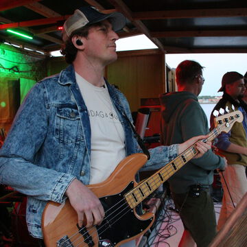 Bassist in Jeansjacke mit Basecap auf der secret stage, Kieler Woche 2024
