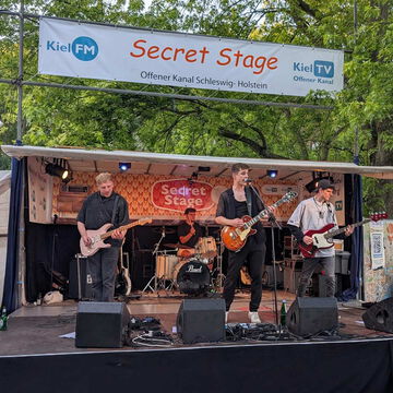 Band mit Gitarren und Schlagzeug auf der secret stage des Offenen Kanals, Kieler Woche 2025
