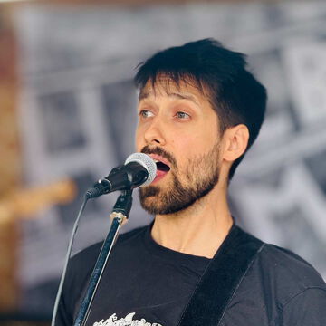 Sänger mit dunklen Haaren und Bart singt ins Mikrofon, secret stage, Kieler Woche 2025